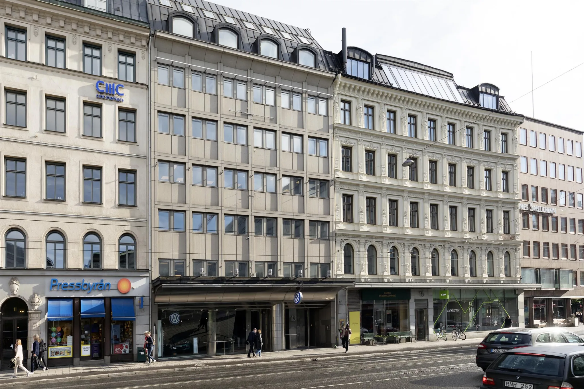 En fasad av flera kontorsbyggnader med stora fönster och affärer på bottenvåningen.