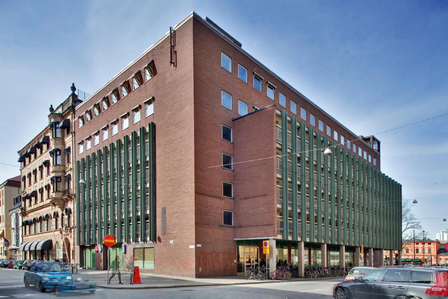 5. En röd tegelbyggnad med gröna fönsterluckor på en stadsgata.