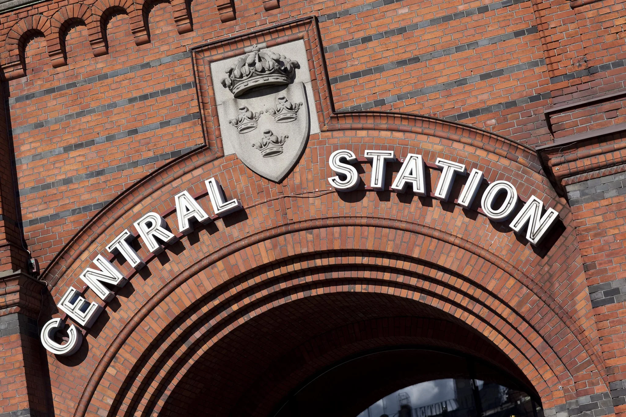 5. Tegelbyggnad med en skylt där det står "Central Station" och en sköld med ett kronat ansikte ovanför texten.