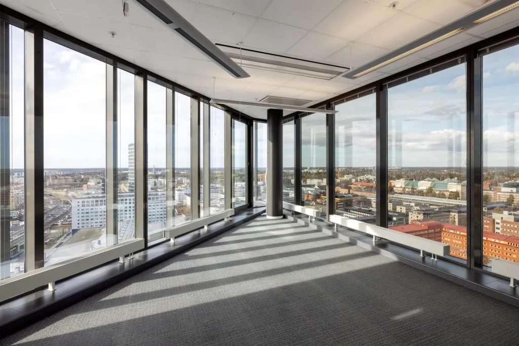 Ett hörnkontor med panoramafönster och utsikt över staden under en klar himmel.