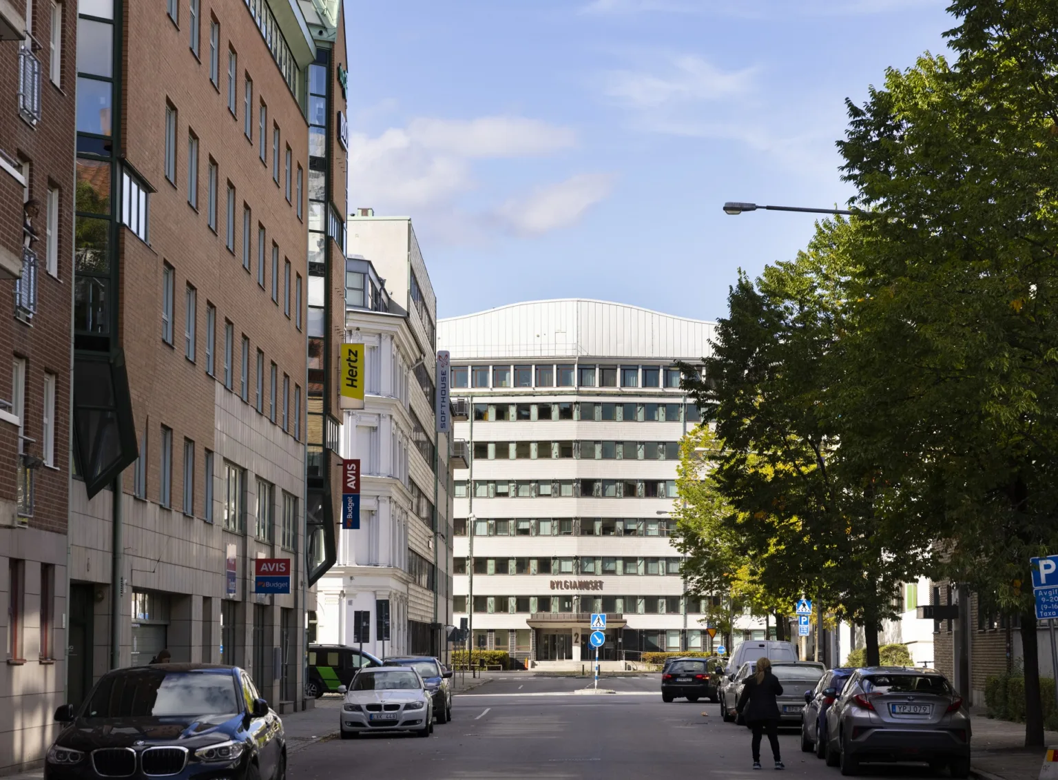 4. En stadsgata kantad av byggnader med ett stort vitt kontorshus i bakgrunden.