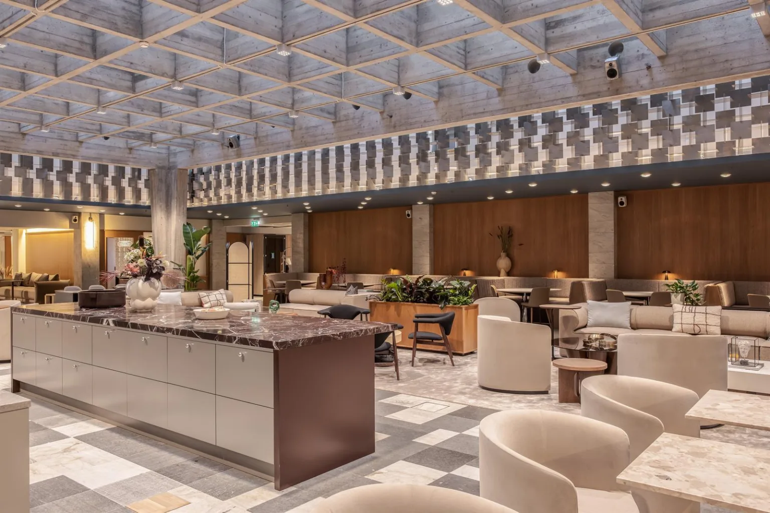 Ett rymligt loungeområde med moderna möbler, marmorbord och en geometrisk design i taket.