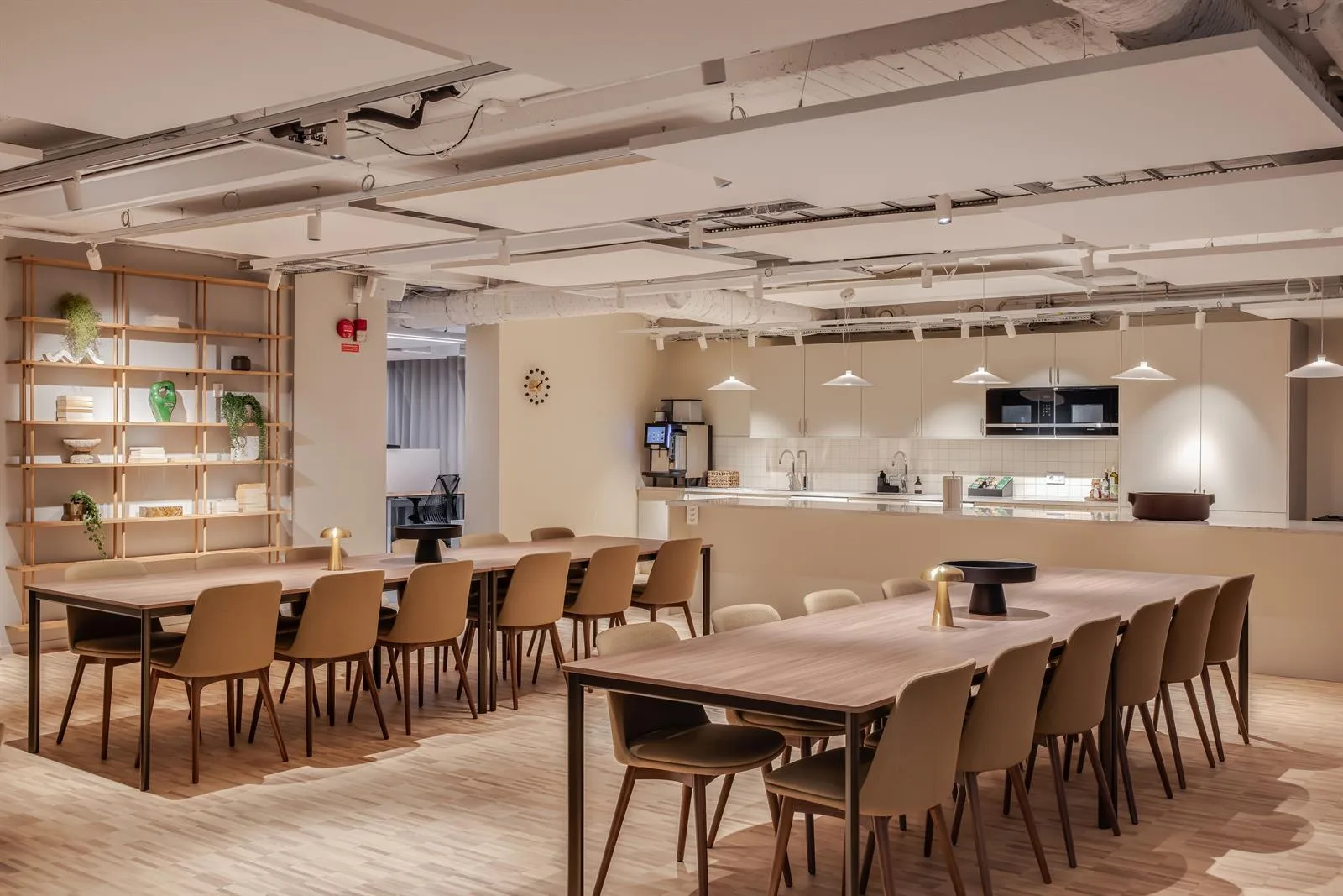 Ett rymligt kök och matplats med flera bord, stolar och en kaffestation i ett öppet, välbelyst utrymme.