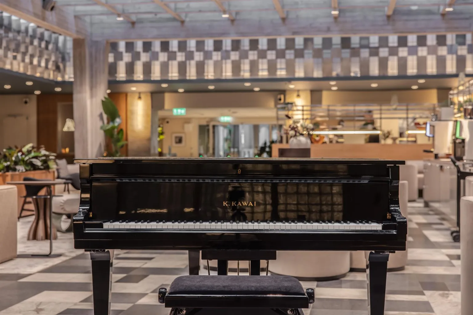 En svart flygel står i ett öppet utrymme med dekorativ belysning och en reception i bakgrunden.