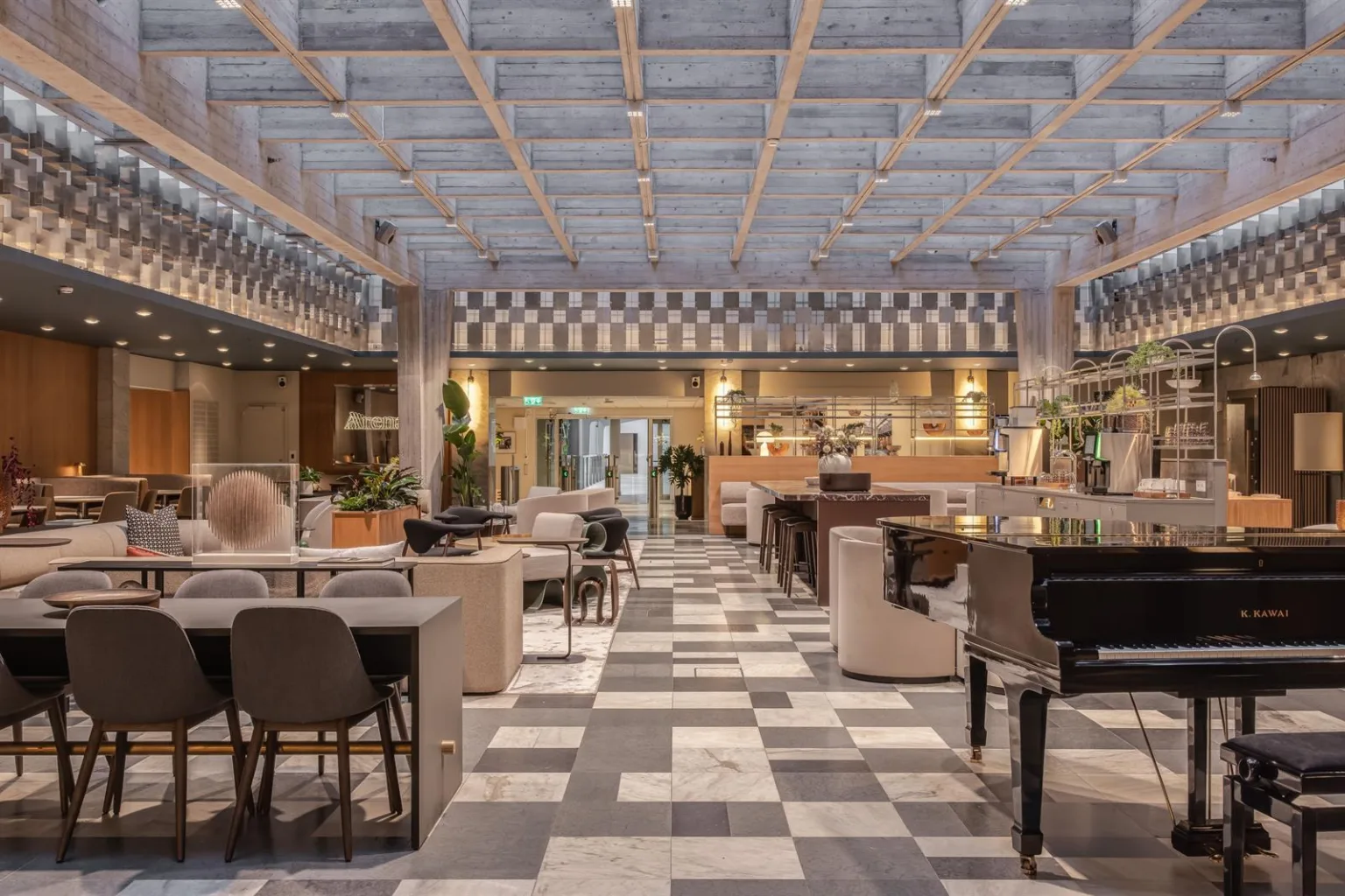 En rymlig restaurang med marmorgolv, bord och stolar, växtdekorationer och en bardisk i bakgrunden.